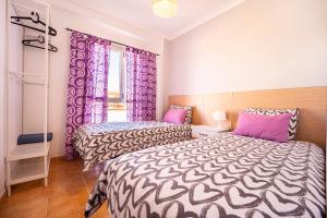 two beds in a room with purple curtains at El Secreto del Norte in Las Palmas de Gran Canaria