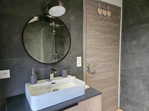 La salle de bains est pourvue d'un lavabo blanc et d'un miroir. dans l'établissement Maison d'une chambre avec sauna jardin amenage et wifi a Les Forges, à Les Forges
