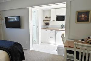 a bedroom with a bed and a kitchen with a desk at Secret Garden Guest Suite in Tauranga