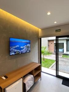 a living room with a flat screen tv on the wall at Vila do Porto Pousada in Morretes