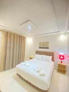 a bedroom with a large white bed with a red lamp at Appartement Chic et Luxueux Corniche Tanger in Tangier