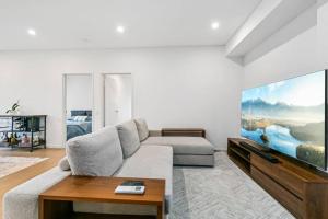 a living room with a couch and a large screen tv at Luxury Waterfront 2 Bed near Olympic Park & Parra in Sydney