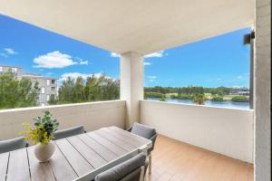 a table and chairs on a balcony with a view of the water at Luxury Waterfront 2 Bed near Olympic Park & Parra in Sydney