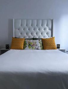 duże białe łóżko z dużym zagłówkiem i poduszkami w obiekcie DMK GUESTHOUSE 2 w Kapsztadzie