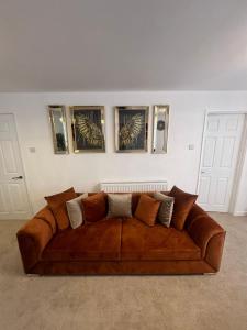 um sofá castanho num quarto com três fotografias na parede em Elegant House em Barnstaple