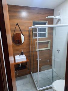 y baño con ducha acristalada y lavamanos. en Suítes Recanto Petrópolis en Petrópolis