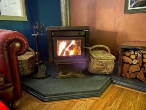 a wood stove in a room with two baskets at The Red Cottage in Wentworth Falls