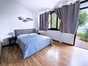a bedroom with a bed and large windows at Villa Anita Apartments in Capo dʼOrlando