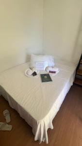 Una cama blanca con dos platos de comida. en Chacara Recanto do Pinheiro en Capão do Leão