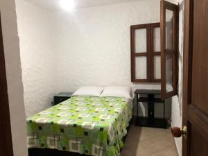 a small bedroom with a bed and a table at CASA HOSPEDAJE PRANA in Jardin