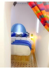 a bedroom with a bed with a blue head board at Dar tisir in Essaouira