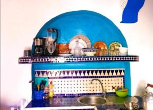 a kitchen with a sink and a blue shelf at Dar tisir in Essaouira