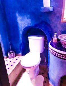a bathroom with a white toilet and a blue wall at Dar tisir in Essaouira