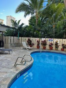 ein blauer Pool mit einem Stuhl und Palmen in der Unterkunft Aloha Surf Hotel -2 blocks from Waikiki Beach in Honolulu