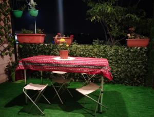 a table with two chairs and a table with a red table cloth at Seleucia DaR Umm Qais in Um Qeis