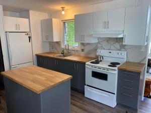 a kitchen with white cabinets and a white stove top oven at La Belle Nature in Saint Ludger de Milot