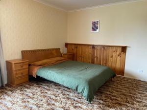 a bedroom with a bed and a wooden headboard at The Vintage Flat - Retro Charm in Tyrolean Village in Jindabyne
