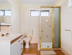 a bathroom with a shower and a toilet and a sink at The Vintage Flat - Retro Charm in Tyrolean Village in Jindabyne