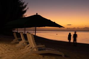 dos personas de pie en la playa bajo una sombrilla en Saipan World Resort, en Susupe