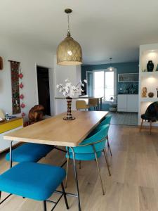 uma sala de jantar com uma mesa e cadeiras azuis em villa cosy 5 minutes de bayonne, 15 minutes des plages em Boucau