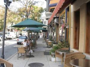 a sidewalk with tables and chairs and an umbrella at Spacious Passyunk Square 3BR House in Philadelphia