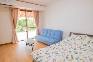 een slaapkamer met een bed en een blauwe bank bij さつきあん in Miyako Island