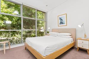 um quarto com uma cama e janelas grandes em Charming Modern Apartment with City Views em Sydney