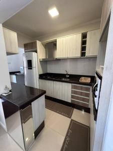 a kitchen with white cabinets and black counter tops at Excelente Apto em Bal. Camboriú in Balneário Camboriú