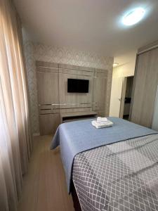 a bedroom with a bed with a blue blanket and a tv at Excelente Apto em Bal. Camboriú in Balneário Camboriú