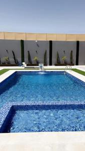 a swimming pool with blue water in front of a building at شاليه نايا in Kerak