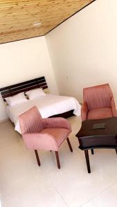 1 dormitorio con 1 cama, 2 sillas y mesa en شاليه نايا, en Kerak