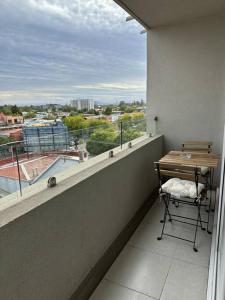 a table and a chair on a balcony with a window at Departamento céntrico Chillán con estacionamiento in Chillán