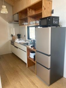 a kitchen with a refrigerator and a microwave at DREAM LIFE Onsen Villa in Niseko