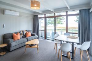 ein Wohnzimmer mit einem Sofa und einem Tisch in der Unterkunft Whispering Sands Beachfront Motel in Gisborne