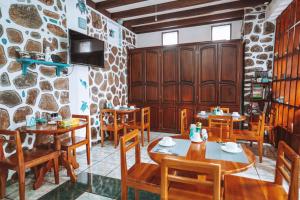 un restaurante con mesas y sillas de madera y una pared de piedra. en Maidith Galapagos Inn en Puerto Ayora