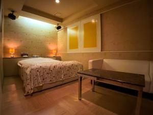 a bedroom with a bed and a table and a couch at ホテル ルヴワール in Nyū