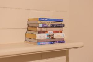 a stack of books sitting on a shelf at Villa City Break for couples 27 mins CHC Airport in Christchurch