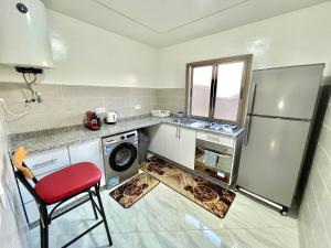 Il comprend une cuisine équipée d'un réfrigérateur et d'une chaise rouge. dans l'établissement A3 Appartement entièrement neuf au cœur de Témara, à Temara