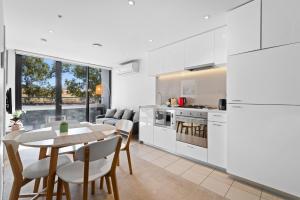 cocina y comedor con mesa y sillas en Bright CBD Apartment 2-Minutes To Gardens & Market, en Melbourne