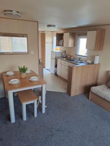 a living room with a table and a kitchen at H13 Sunnymede in Ingoldmells