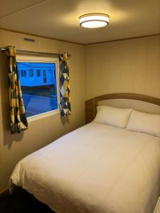 ein Schlafzimmer mit einem weißen Bett und einem Fenster in der Unterkunft H13 Sunnymede in Ingoldmells