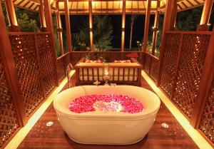 a bath tub filled with pink flowers on a balcony at Anapuri Villas in Ketewel