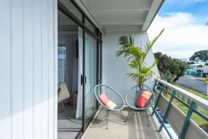 a balcony with two chairs and a plant at Whispering Sands Beachfront Motel in Gisborne