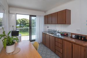 a kitchen with wooden cabinets and a table with a plant at Whispering Sands Beachfront Motel in Gisborne