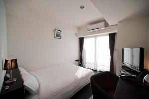 Habitación de hotel con cama y TV en Omura Station Hotel en Omura