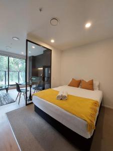um quarto com uma cama grande e um cobertor amarelo em Rare park view gem em Auckland