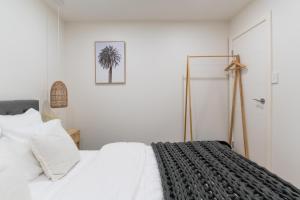 a bedroom with a white bed and a palm tree at Hills Hideaway in Bridgewater