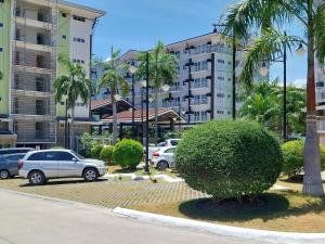 a parking lot with parked cars and palm trees at Stay and Fly at Amani Grand Resort Residences in Mactan