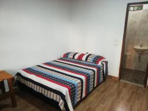 1 cama con manta a rayas en una habitación en Encanto de agua, Jardin, en Jardín