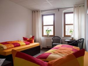 2 Betten in einem Zimmer mit 2 Stühlen und Fenstern in der Unterkunft Sefano Low Budget Hotel in Nossen